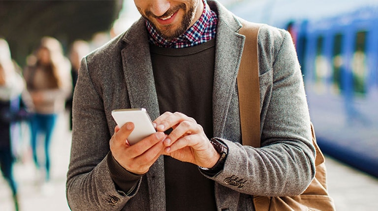 Man looking at phone on train platform