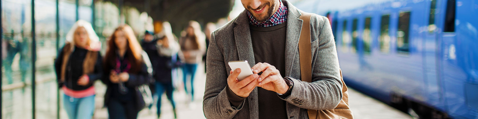 Man looking at phone on train platform