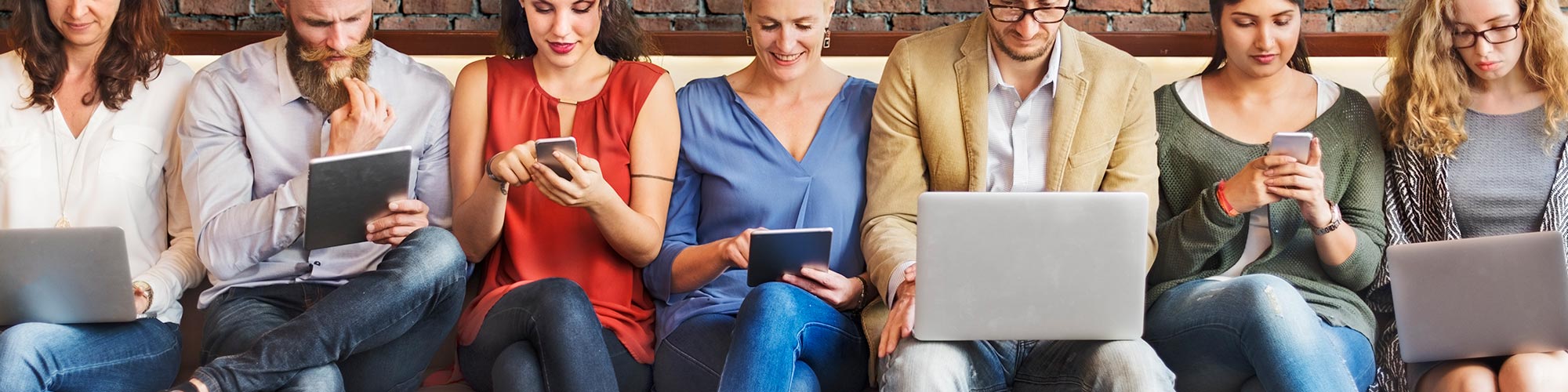 Group sitting on couch looking at smart devices